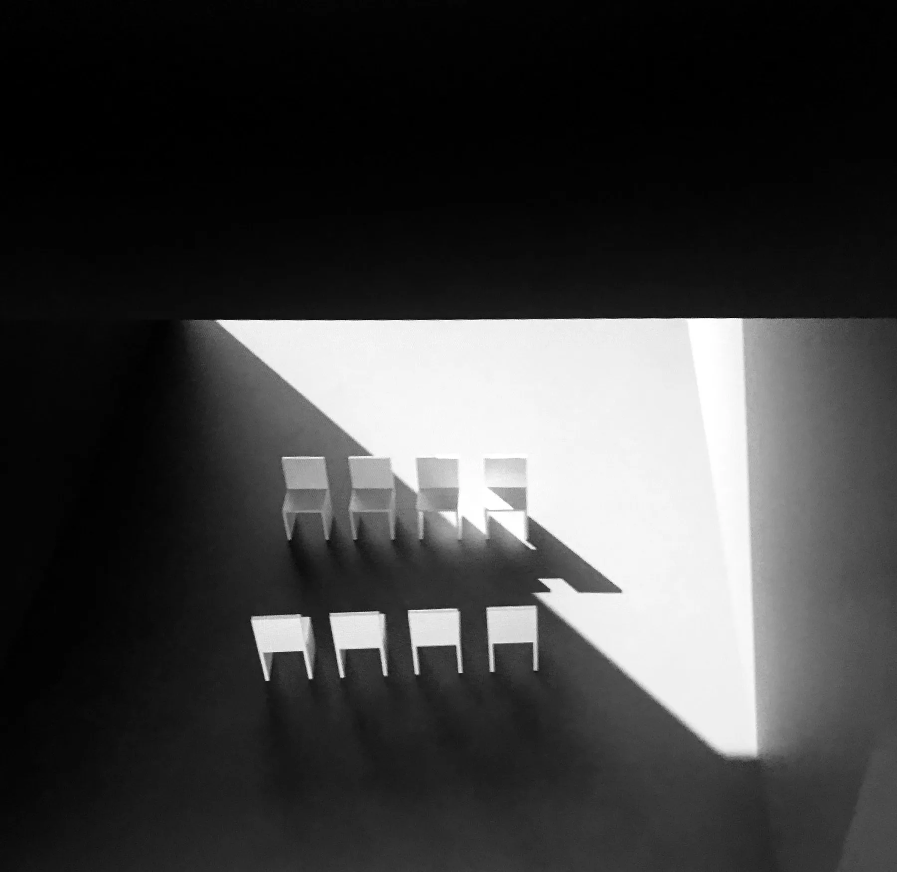 Dos filas de sillas de maqueta atravesadas por una diagonal de luz Dos filas de sillas de maqueta atravesadas por una diagonal de luz